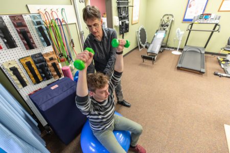 the physical therapy member helps the patient to lift his arms